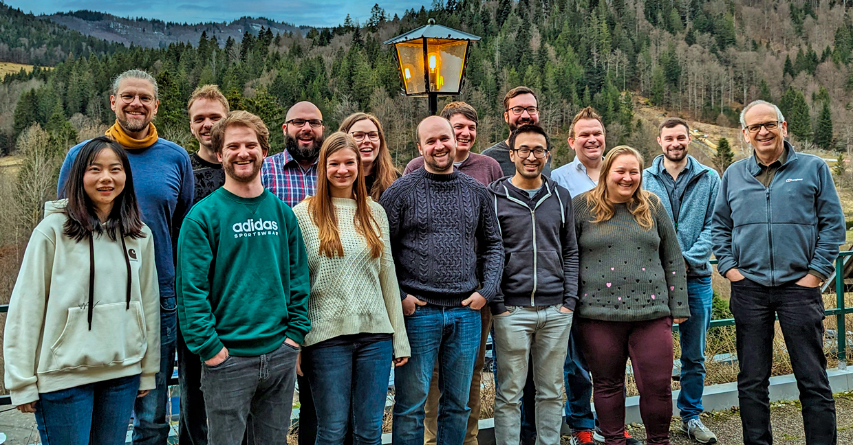 Gruppe von Menschen lächelt vor einer Berglandschaft.